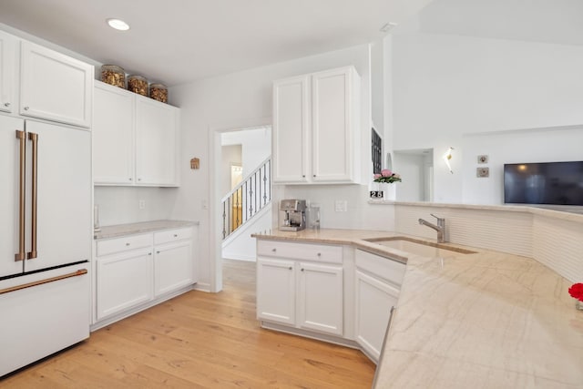 kitchen featuring paneled built in refrigerator, light wood finished floors, a sink, and white cabinetry