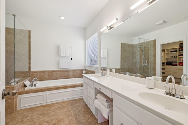 bathroom with a shower stall, a walk in closet, a sink, and tile patterned floors