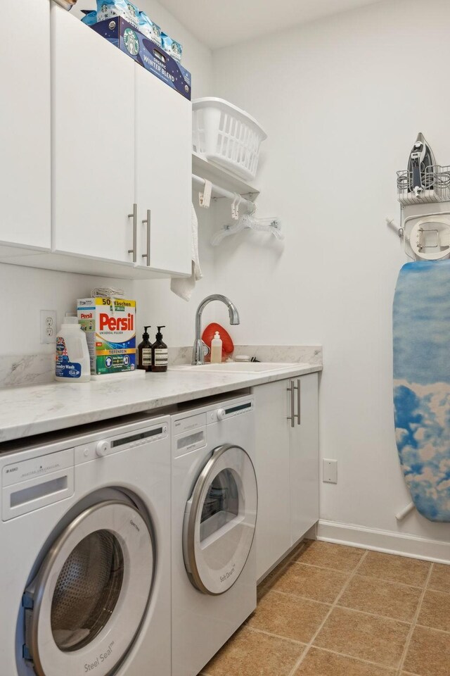 laundry room with cabinet space, light tile patterned floors, baseboards, separate washer and dryer, and a sink