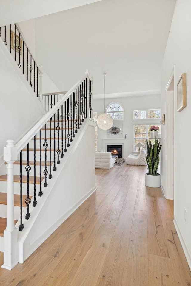 stairs with hardwood / wood-style flooring, baseboards, and a glass covered fireplace