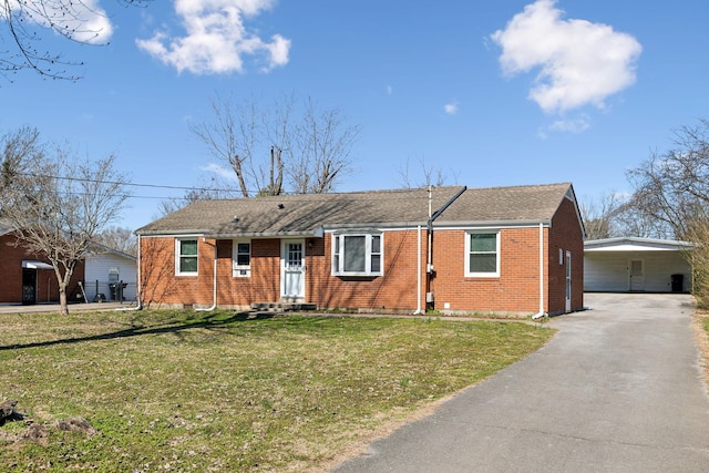 single story home with aphalt driveway, an attached carport, brick siding, and a front yard