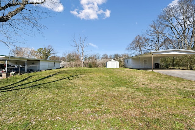 view of yard with a carport, an outbuilding, driveway, and a storage shed