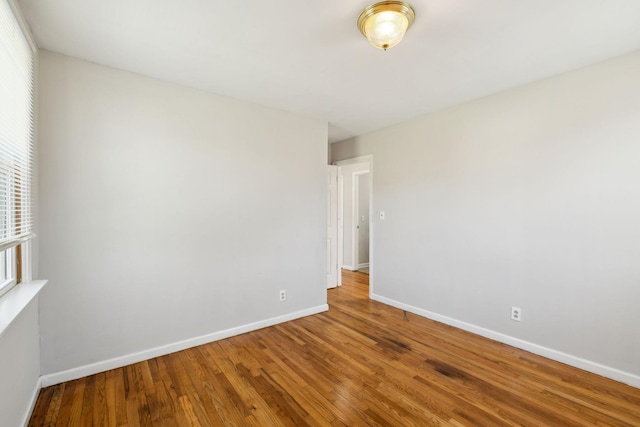 spare room with baseboards and wood finished floors