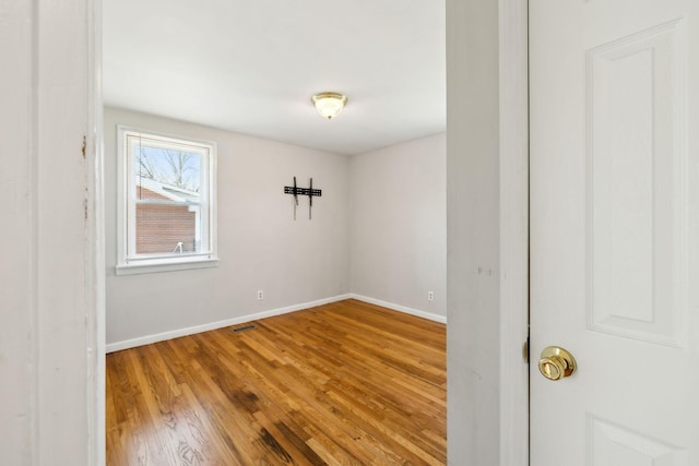 unfurnished room with visible vents, baseboards, and wood finished floors