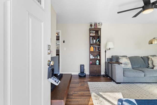 living area with a ceiling fan, dark wood finished floors, and baseboards