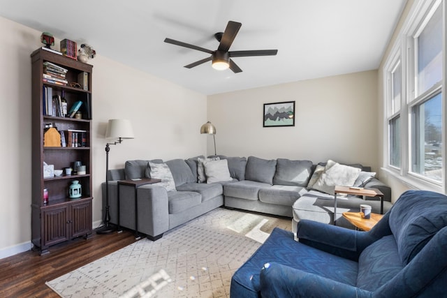 living room with dark wood-style floors, a ceiling fan, and baseboards