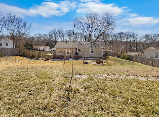 rear view of property with a yard, a fenced backyard, and a garden