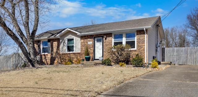 view of front facade featuring a front yard, fence, and brick siding