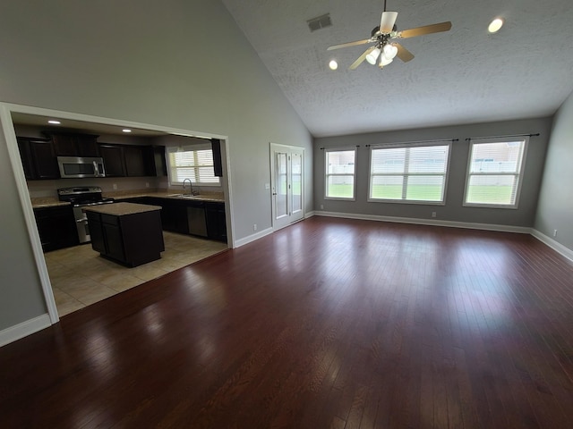 kitchen featuring stainless steel appliances, a sink, a kitchen island, open floor plan, and light countertops