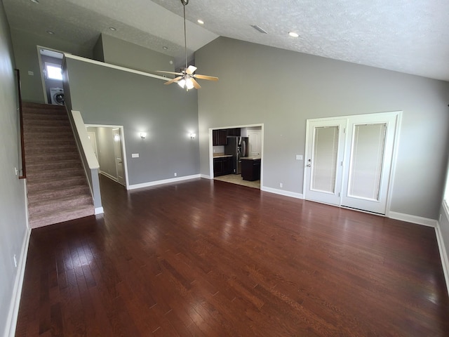 unfurnished living room with baseboards, a ceiling fan, dark wood-style floors, stairs, and a textured ceiling