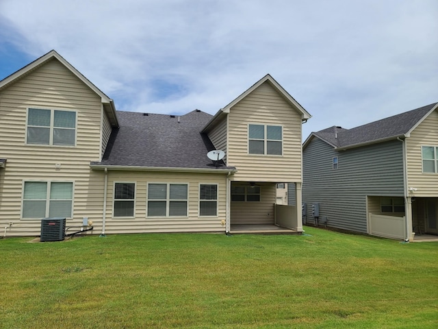 rear view of property featuring a yard, a shingled roof, a patio, and cooling unit