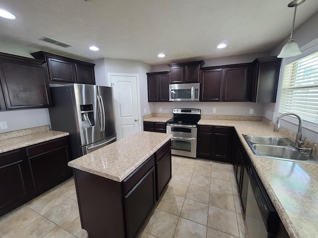 kitchen with visible vents, appliances with stainless steel finishes, hanging light fixtures, light countertops, and a sink