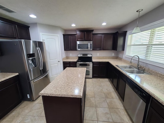 kitchen with visible vents, a kitchen island, appliances with stainless steel finishes, light countertops, and a sink