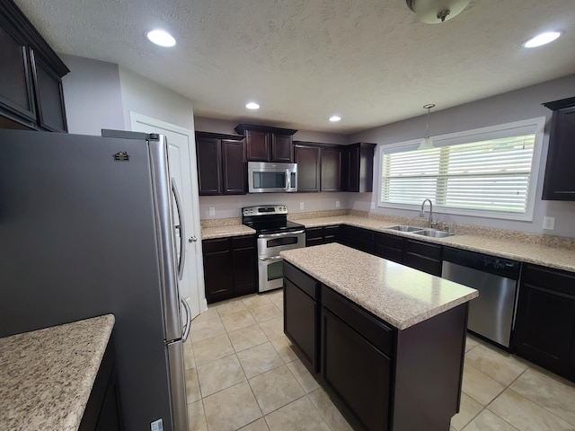 kitchen featuring a kitchen island, a sink, light countertops, appliances with stainless steel finishes, and pendant lighting