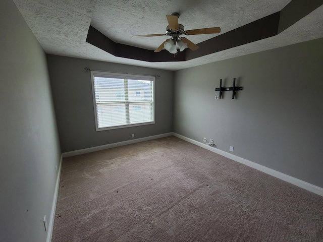 carpeted spare room with baseboards, a raised ceiling, and a textured ceiling