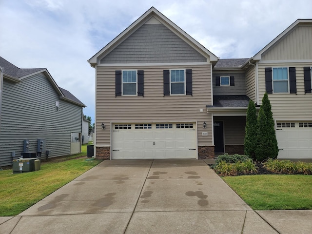 craftsman inspired home with concrete driveway, an attached garage, a front lawn, and central air condition unit