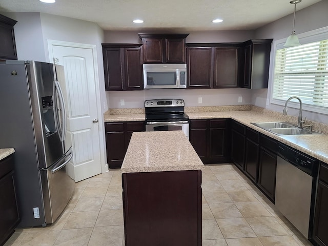 kitchen with light tile patterned floors, a kitchen island, appliances with stainless steel finishes, decorative light fixtures, and a sink