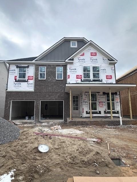 view of front of home with an attached garage, a porch, and brick siding