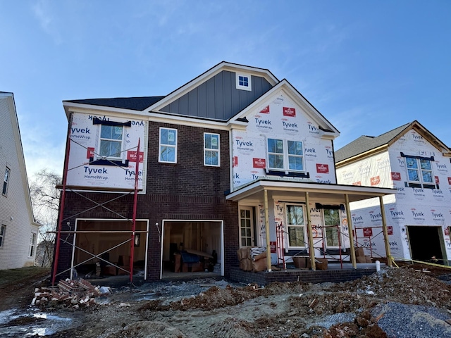 property under construction featuring board and batten siding, brick siding, a porch, and a garage