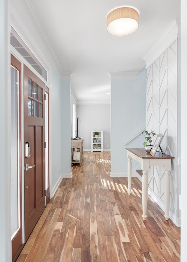 hallway featuring light wood finished floors, baseboards, and crown molding