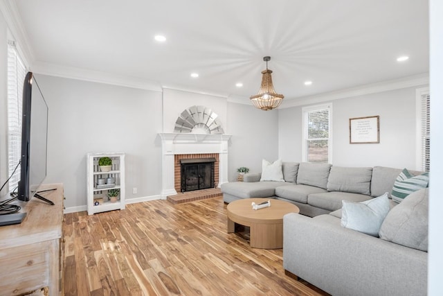 living area with baseboards, ornamental molding, a fireplace, and light wood-style floors