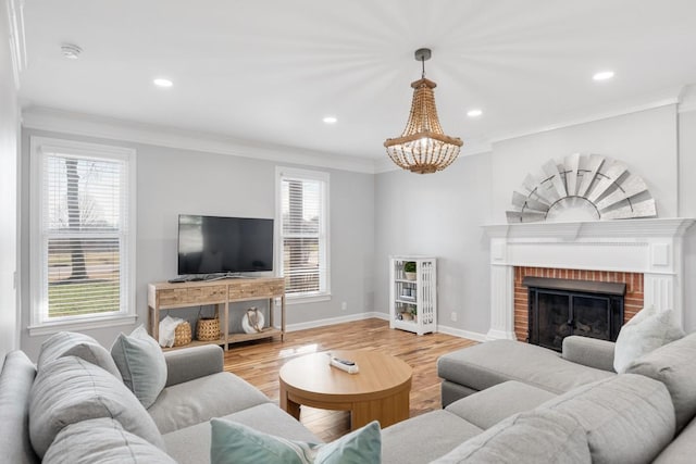 living area with ornamental molding, light wood-type flooring, a brick fireplace, and baseboards