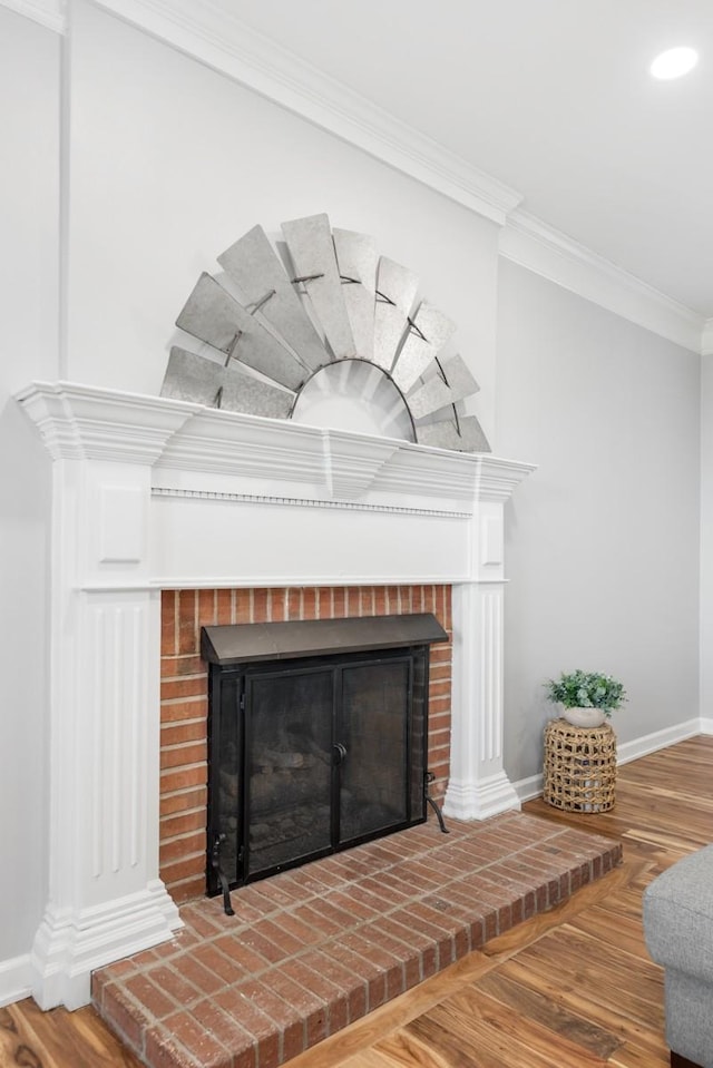 room details featuring a brick fireplace, baseboards, ornamental molding, and wood finished floors