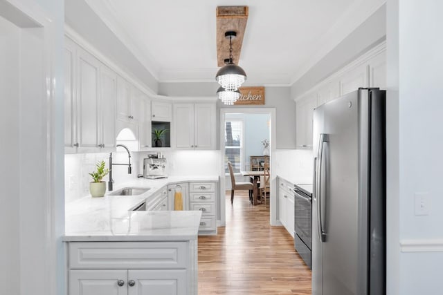 kitchen with crown molding, white cabinetry, a sink, and freestanding refrigerator