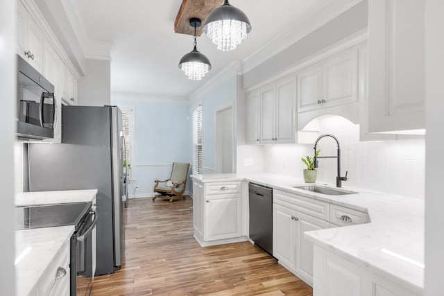 kitchen with a sink, white cabinets, black appliances, an inviting chandelier, and crown molding