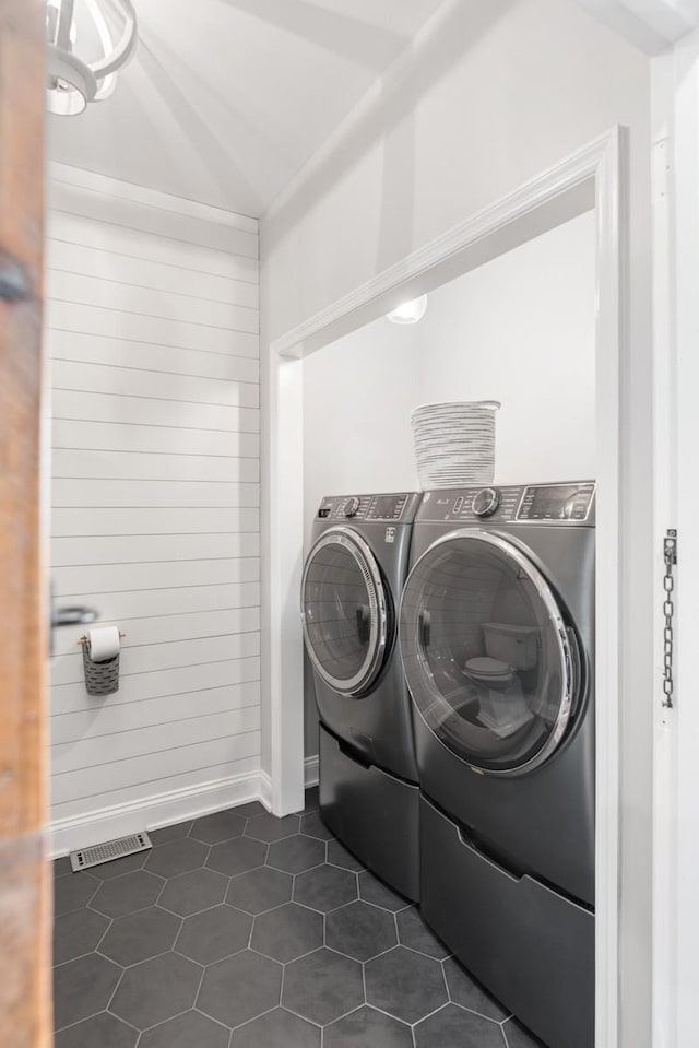 laundry area with laundry area, visible vents, baseboards, dark tile patterned flooring, and washing machine and dryer