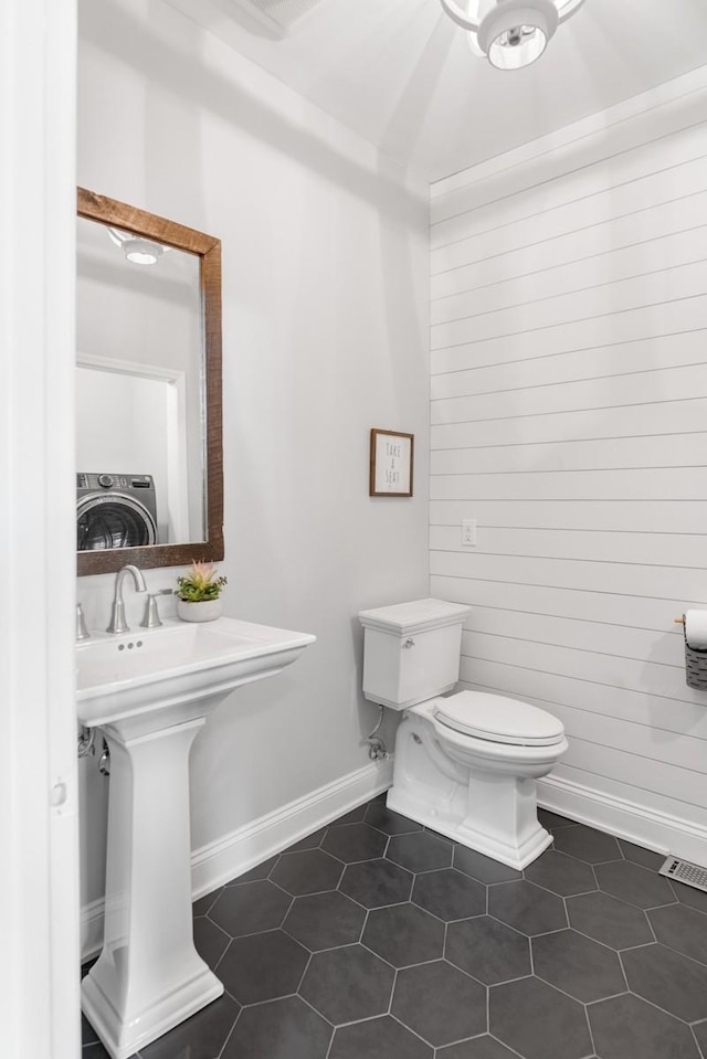 bathroom featuring washer / dryer, baseboards, visible vents, toilet, and tile patterned floors