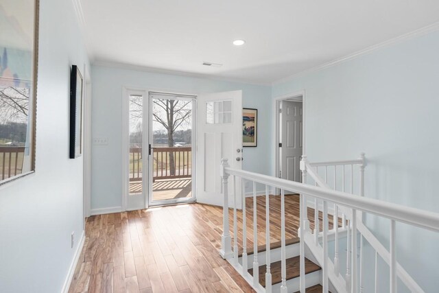 entryway featuring baseboards, wood finished floors, visible vents, and crown molding