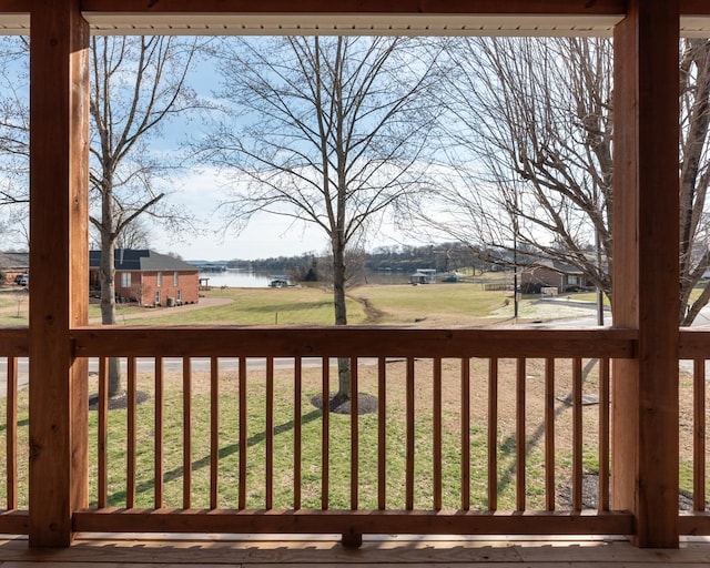 wooden terrace featuring a water view and a yard