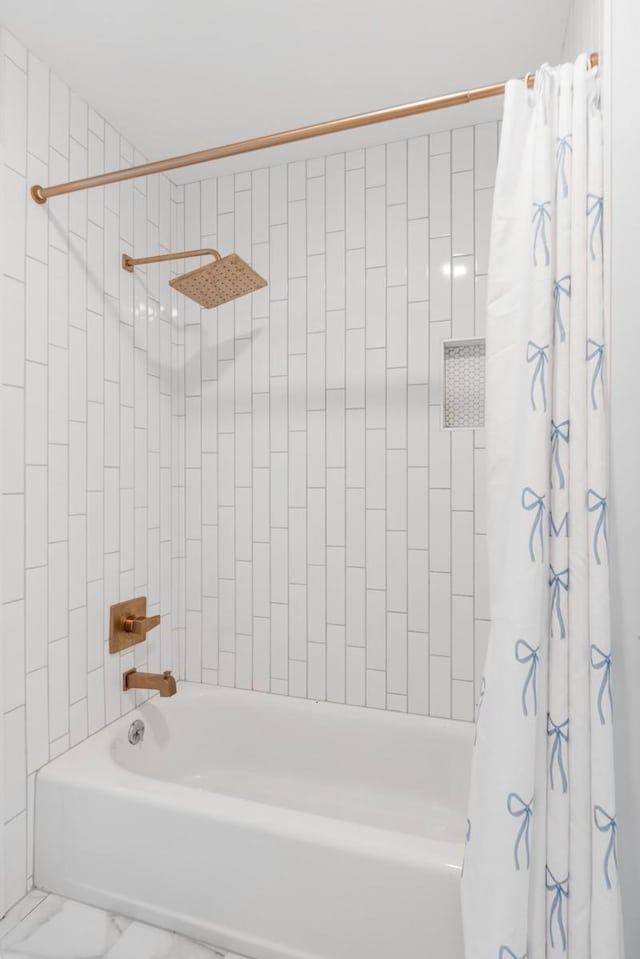 full bath featuring marble finish floor and shower / tub combo