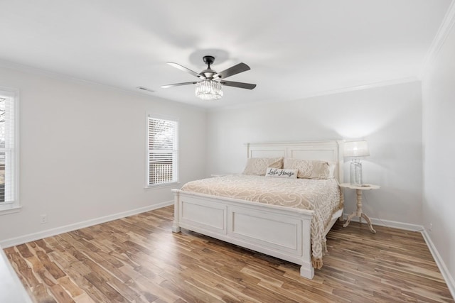 bedroom with crown molding, visible vents, light wood-style floors, ceiling fan, and baseboards