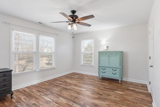 unfurnished bedroom with a ceiling fan, wood finished floors, visible vents, and baseboards