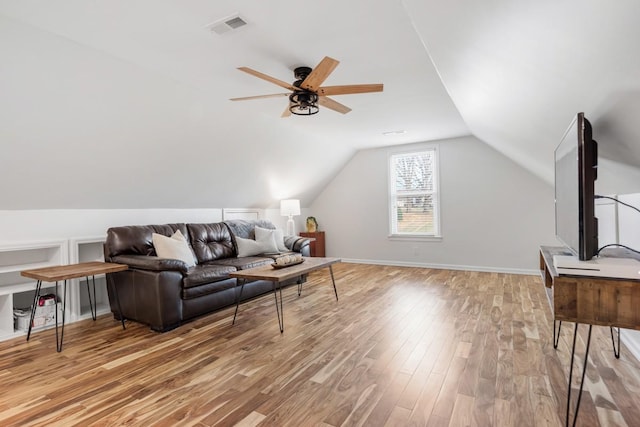 living area featuring lofted ceiling, visible vents, a ceiling fan, wood finished floors, and baseboards