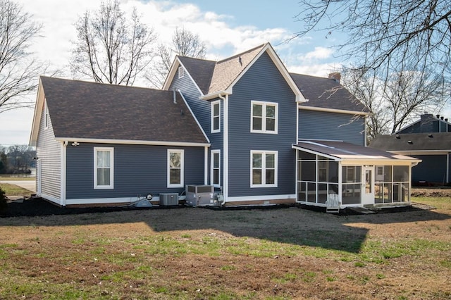 back of property with central air condition unit, a sunroom, a yard, roof with shingles, and a chimney