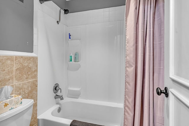 full bath featuring toilet, tile walls, and shower / bathtub combination with curtain