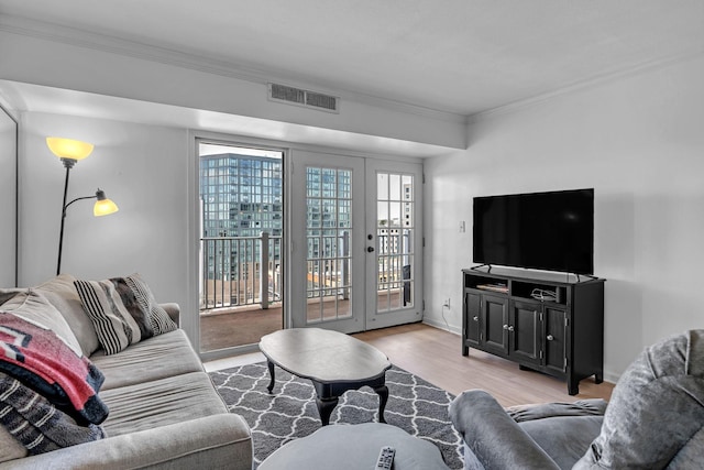 living area with french doors, crown molding, visible vents, light wood-style flooring, and baseboards