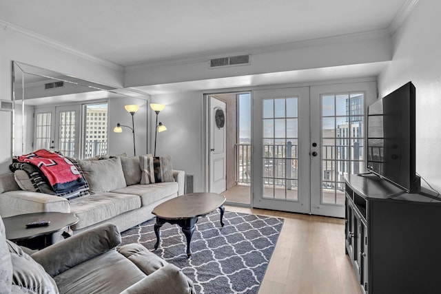 living room with french doors, light wood-style floors, visible vents, and crown molding