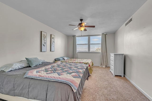 bedroom with baseboards, visible vents, light colored carpet, ceiling fan, and a water view