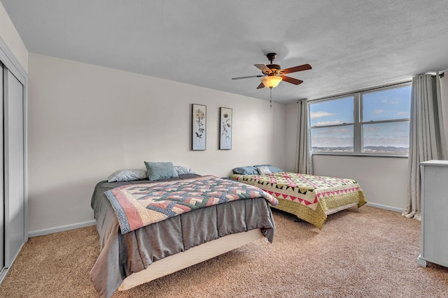 bedroom with light carpet, a closet, a ceiling fan, and baseboards