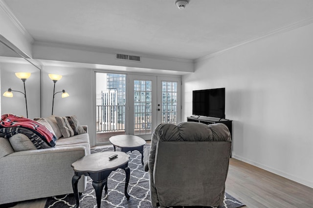 living area featuring baseboards, visible vents, ornamental molding, wood finished floors, and french doors