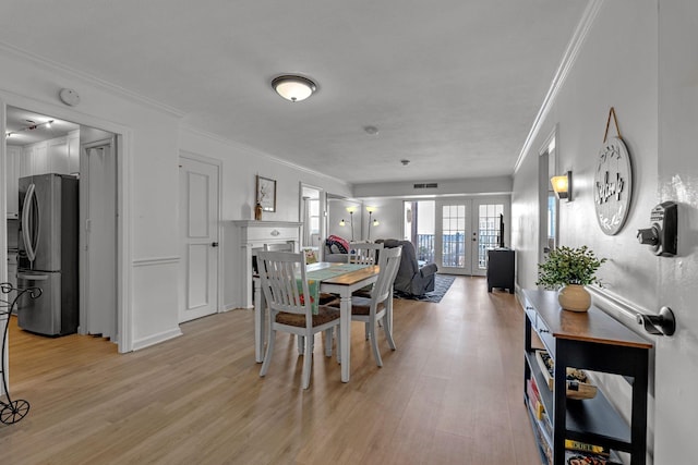 dining space with crown molding, french doors, visible vents, and light wood-style floors