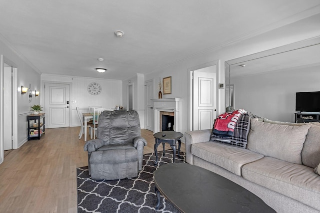 living area with crown molding, a fireplace, and wood finished floors