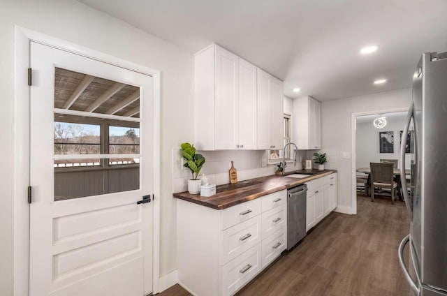 kitchen with butcher block countertops, a sink, white cabinets, appliances with stainless steel finishes, and decorative backsplash