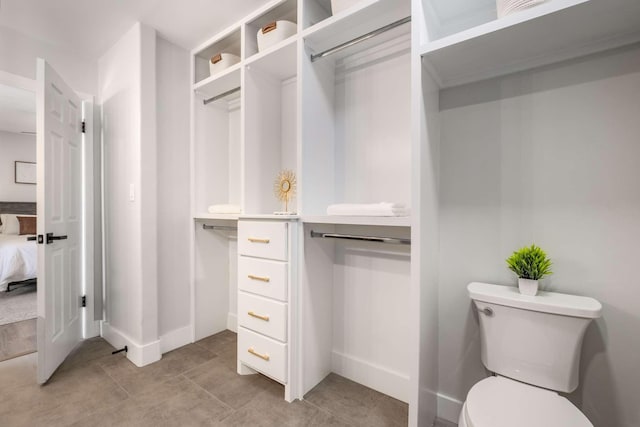 bathroom with baseboards, connected bathroom, and toilet