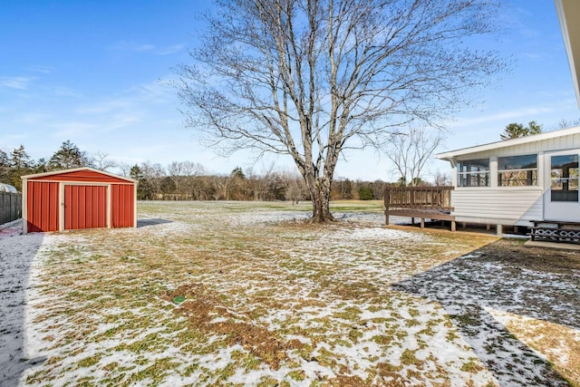 snowy yard featuring a storage shed, an outbuilding, and a sunroom