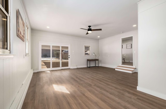 unfurnished living room with dark wood-style floors, a ceiling fan, and baseboards